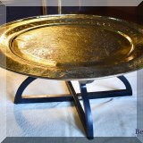 F12. Intricately etched Moroccan brass tray top coffee table with black base. 17”h x 38”w 